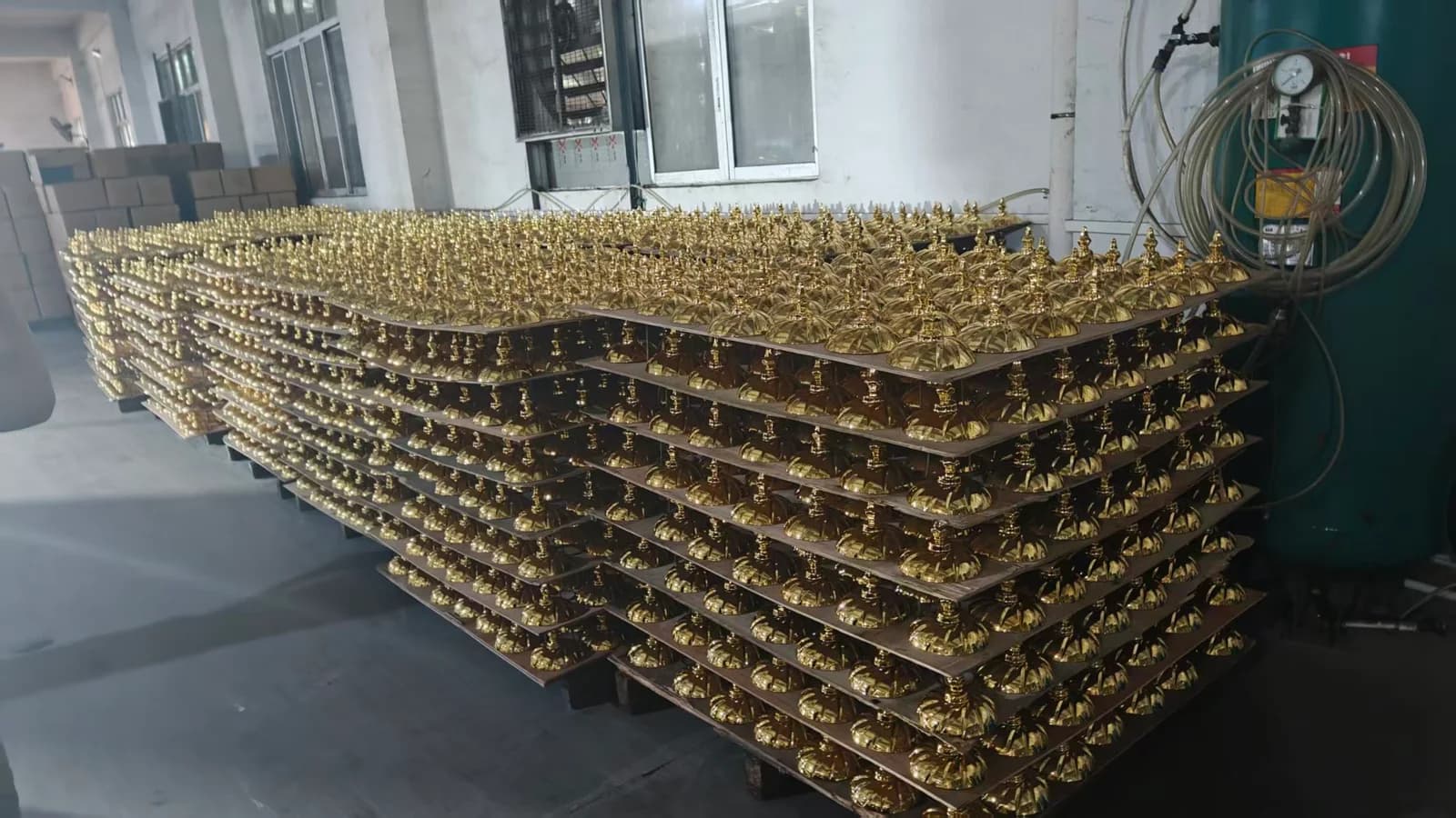 Rows of gold-colored decorative lids arranged in layers on trays.